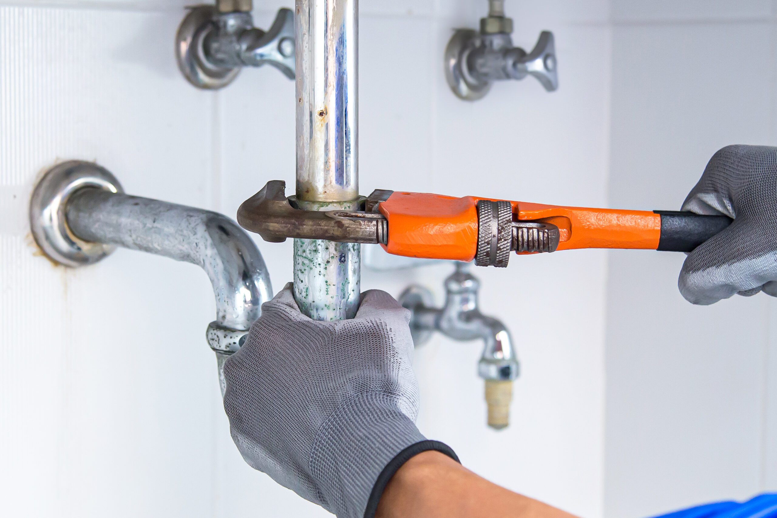 Technician plumber using a wrench to repair a water pipe under the sink. Concept of maintenance, fix water plumbing leaks, replace the kitchen sink drain, cleaning clogged pipes is dirty or rusty.